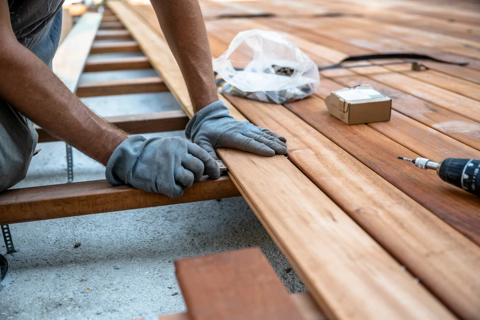 Chantier extérieur avec ouvrier en salopette bleue lissant une dalle de béton fraîchement coulée à l'aide d'une taloche